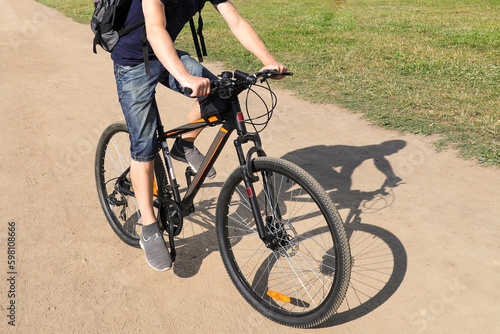 Fototapeta Naklejka Na Ścianę i Meble -  A man in shorts and a black T-shirt rides a bicycle