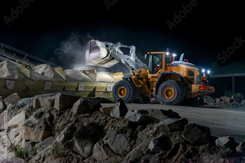 Heavy construction and mining machinery unloading gravel into silos on the night shift.