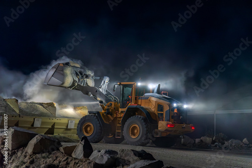 Heavy construction and mining machinery unloading gravel into silos on the night shift.