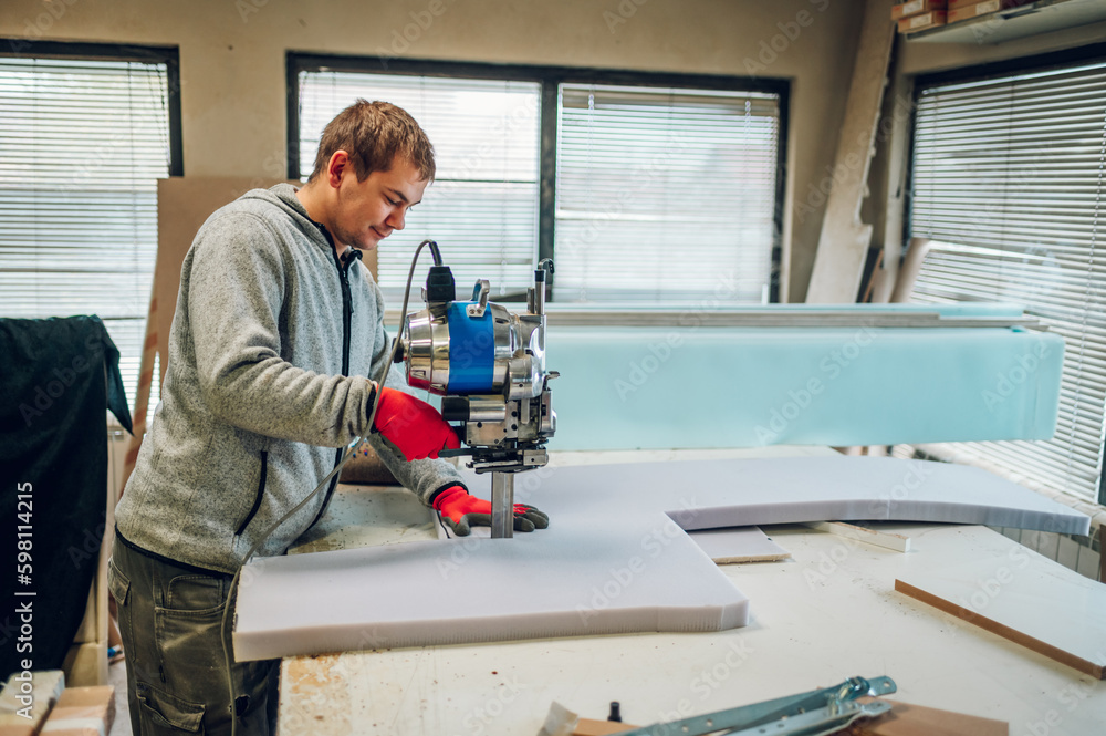Profile view of a worker using a foam cutter at his furniture workshop. Profile view of a worker using a foam cutter at his furniture workshop.