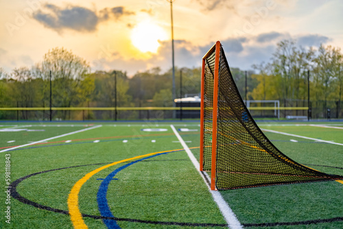 Dramatic late afternoon photo of a lacrosse goal on a synthetic turf field before a night game.
 photo