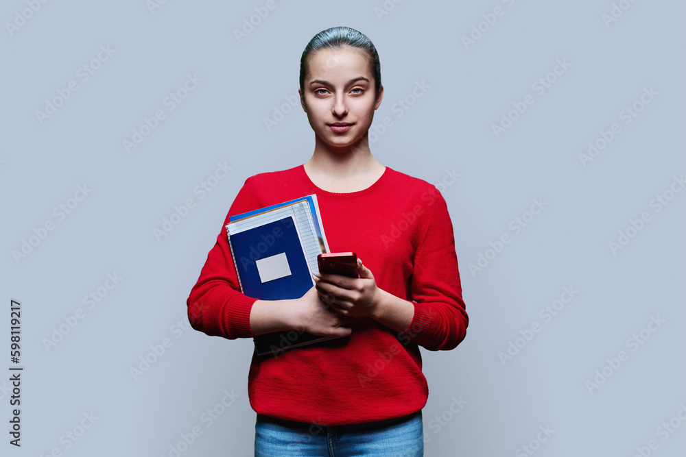 Portrait of teen girl high school student with smartphone on grey background Portrait of teen girl high school student with smartphone on grey background