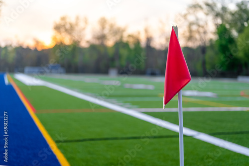 Late afternoon photo of the corner of a synthetic turf soccer field with a red flag.