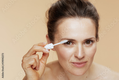 woman with brow brush isolated on beige