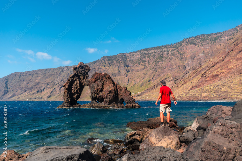 A young man in the touristic icon of El Hierro island called El Roque de la Bonanza, Canary Islands, Spain. Created by volcanic activity