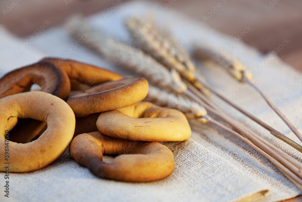 Homemade baking. Dry bagels on a napkin against the background of spikelets of wheat