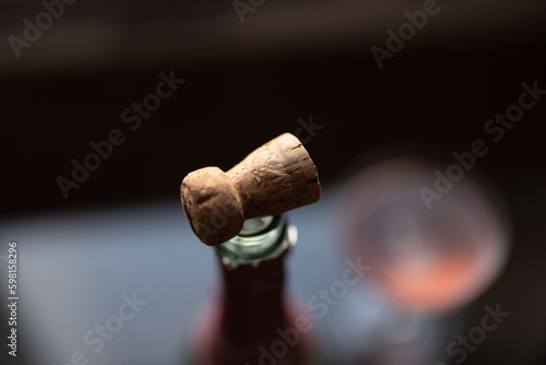 Cork on a bottle of pink champagne on a glass table by a window at sunset