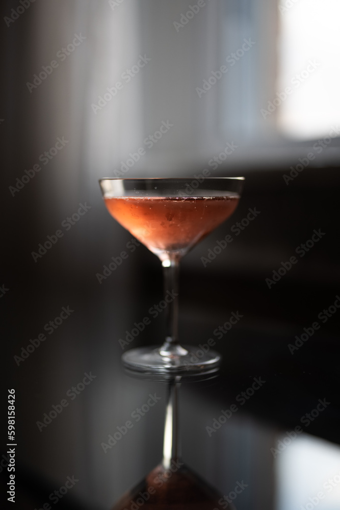 Glass of pink champagne on a glass table by a window at sunset