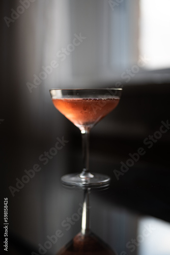 Glass of pink champagne on a glass table by a window at sunset