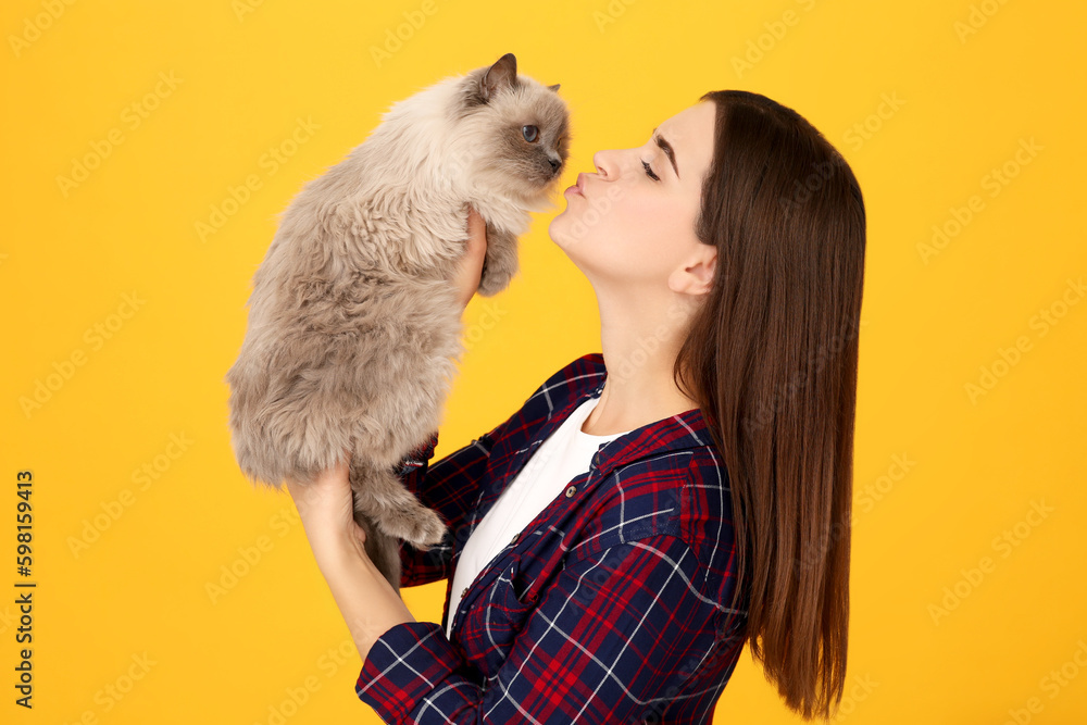Woman kissing her cute cat on orange background Woman kissing her cute cat on orange background