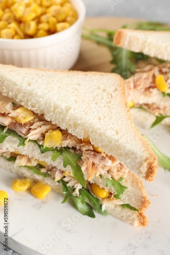 Delicious sandwiches with tuna, corn and greens on serving board, closeup