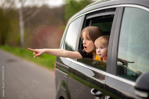 Foto Happy brother and sister looking out car window , point the finger to the side a