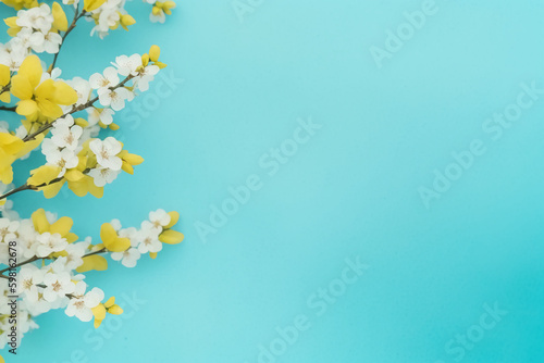 Spring flowers on blue yellow pastel background top view in flat lay style. AI generative © SANGHYUN