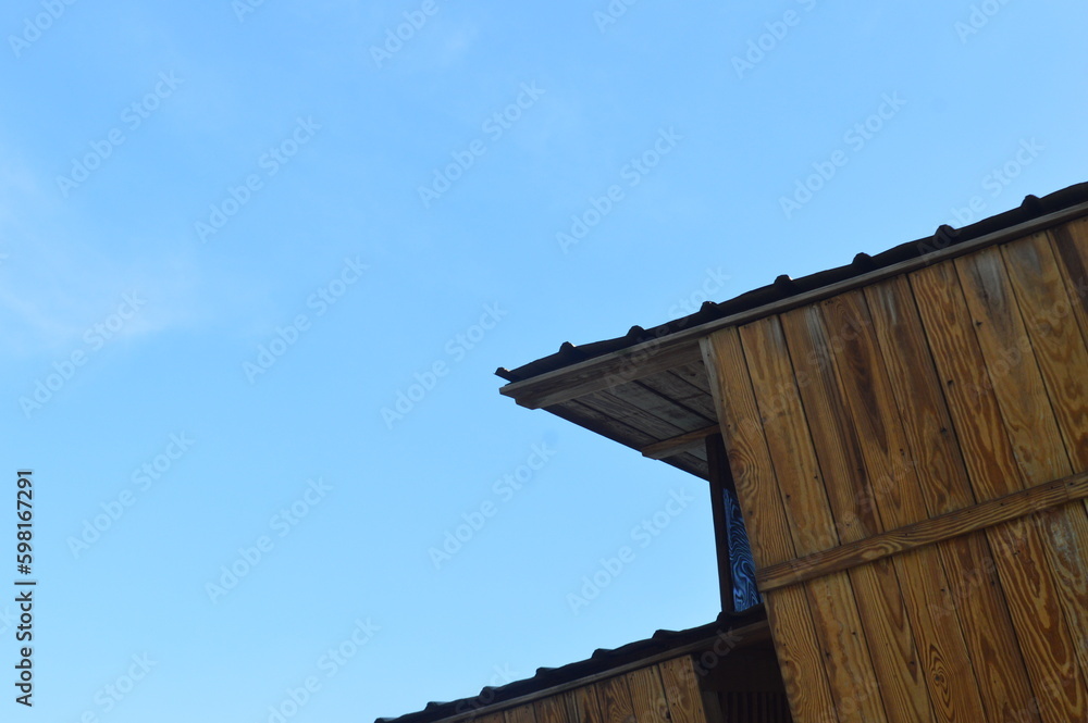 Low angle view of futuristic architecture, wooden villa, against bright blue sky and white clouds, with negative space.