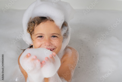 Fotografija Kids shampoo. Child bathes in a bath with foam.