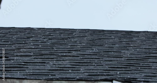 A hail storm sends hail down on top of a roof