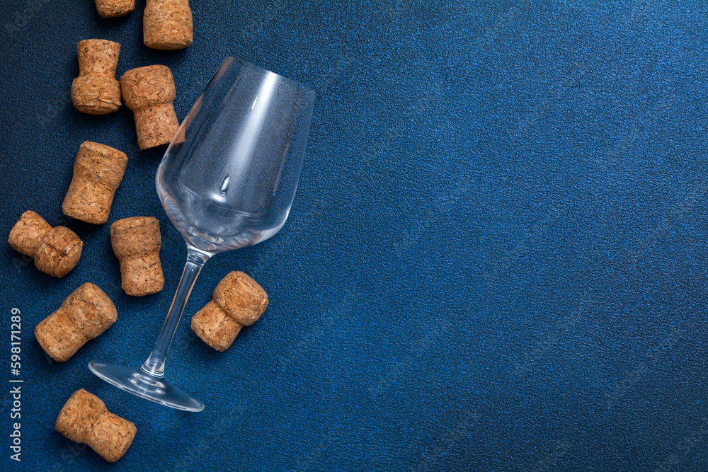Glass empty glass and wine corks . on a blue background