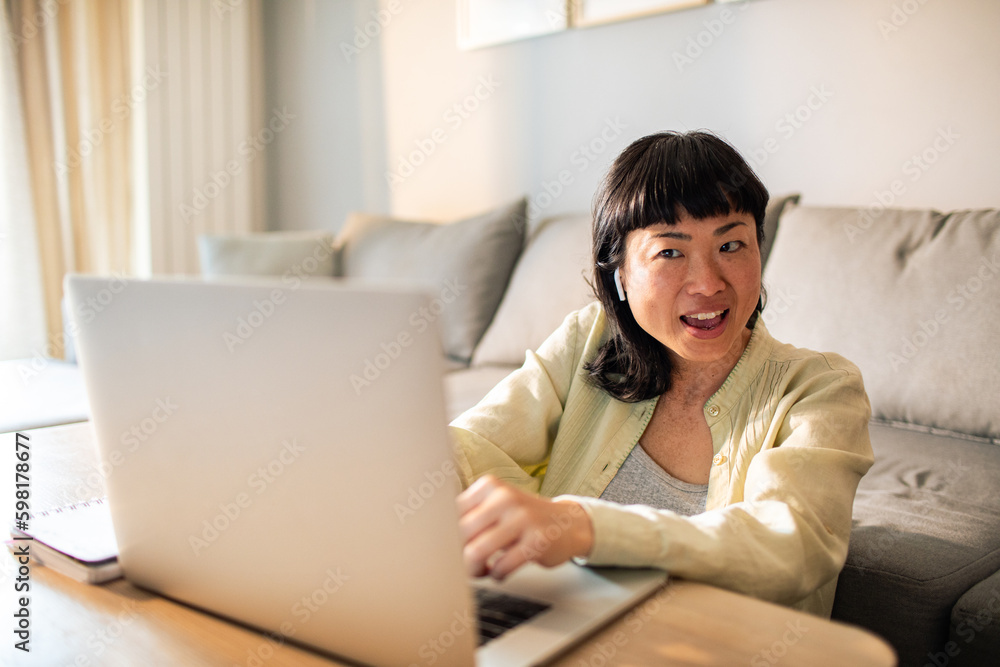 Young Japanese Woman using a laptop on a couch Young Japanese Woman using a laptop on a couch