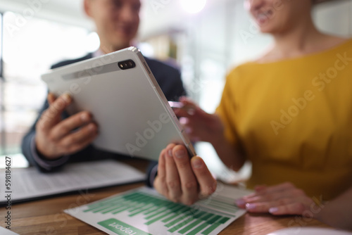 Man shows woman accounting information on website via tablet