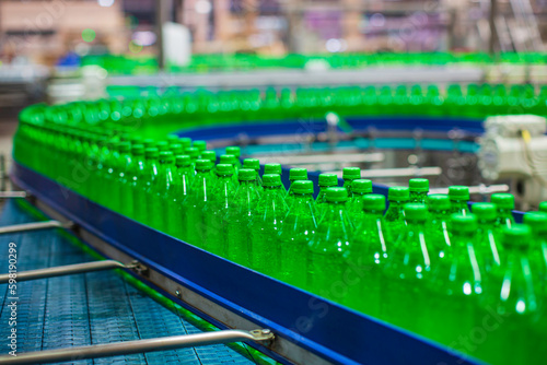 Beverage factory interior. Conveyor flowing with bottles for juice green
