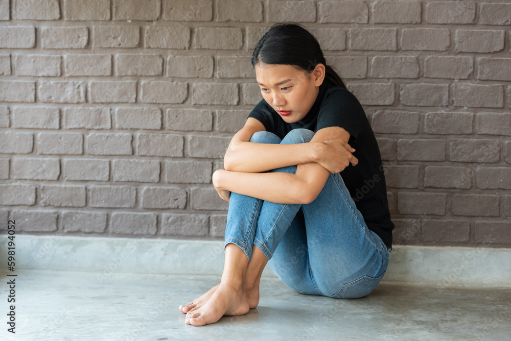 depressing woman is hugging knees on the floor. sad woman hug her knee