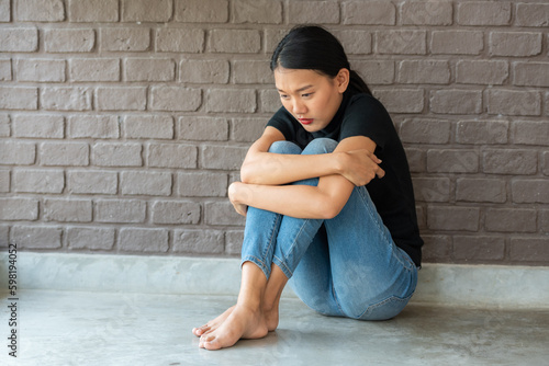 depressing woman is hugging knees on the floor. sad woman hug her knee and cry sitting alone in empty room. alone sadness anxiety grief girl sit hugging knees photo