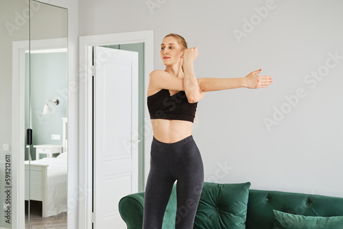 Fototapeta Naklejka Na Ścianę i Meble -  Young woman in sportswear exercising in her living room