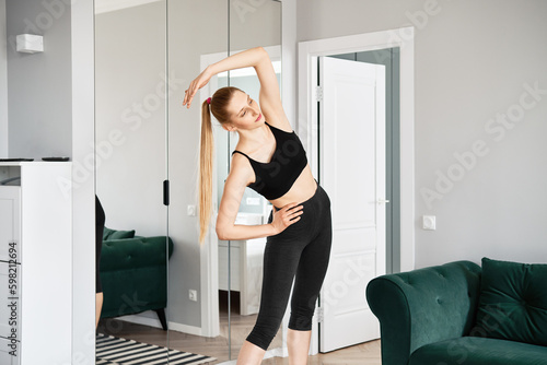 Active blonde woman does bending exercises at home photo
