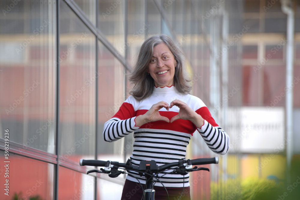 Naklejka premium Smiling senior woman making a heart sign with her hands