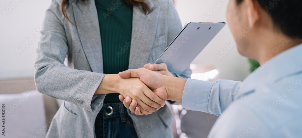 Business men and women shake hands confidently at an office meeting.