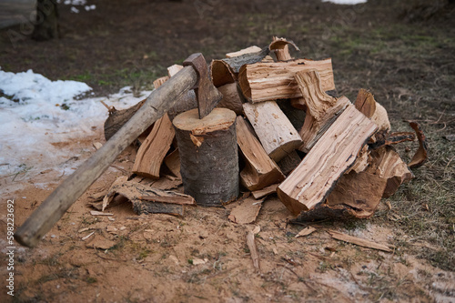 Still life with a wood-burning wooden handle axe for making fire and firewood for fire heat in the winter in a rustic style. Ax and firewood in the yard. Cutting wood in the forest for making fire