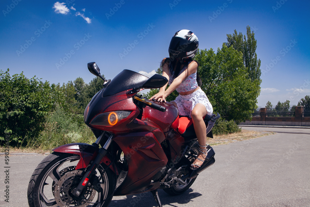 A woman on a motorcycle is wearing a helmet and a white skirt. A woman on a motorcycle is wearing a helmet and a white skirt.
