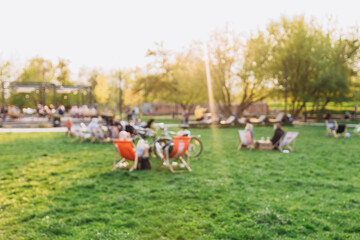 Blurred garden with lighting sunset. Public park with people. Blurred image of people in day in city park background