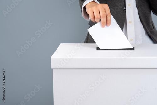 A voter holds vote ballot paper in the ballot box. Election concept.