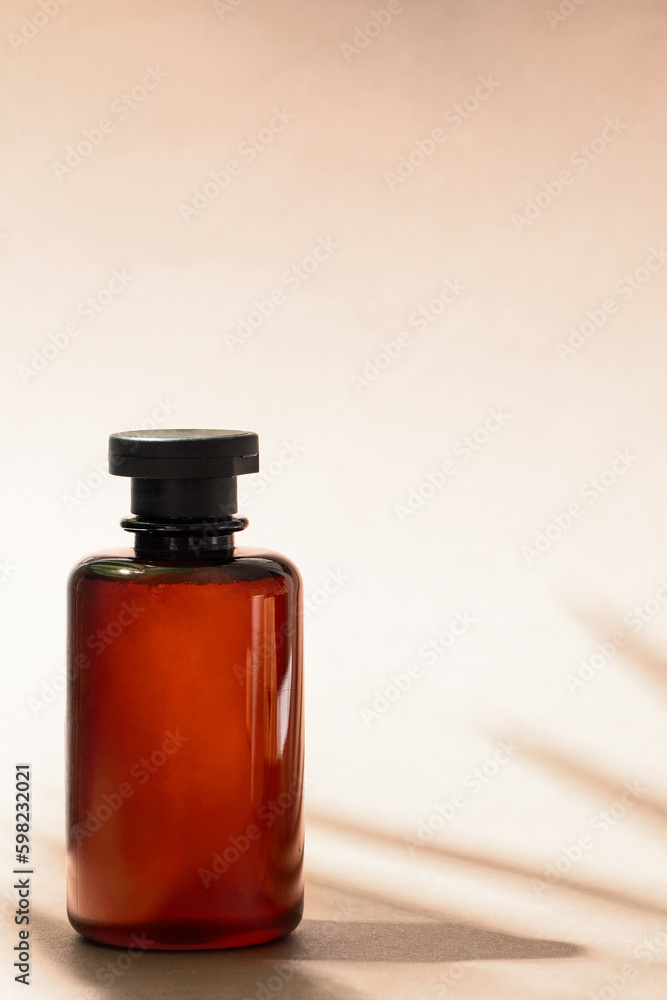 Abstract cosmetic bottle at beige background with palm leaf shadow. Shampoo, bath gel or lotion aesthetic image Abstract cosmetic bottle at beige background with palm leaf shadow. Shampoo, bath gel or lotion aesthetic image
