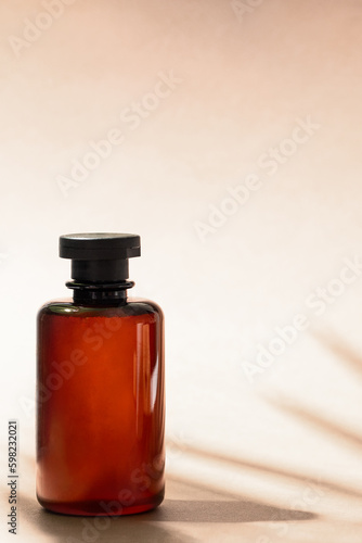 Abstract cosmetic bottle at beige background with palm leaf shadow. Shampoo, bath gel or lotion aesthetic image