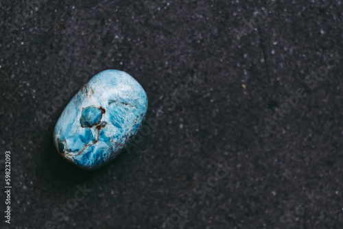 Galet pierre roulée polie apatite sur un fond noir avec espace vide - Minéral naturel	 photo