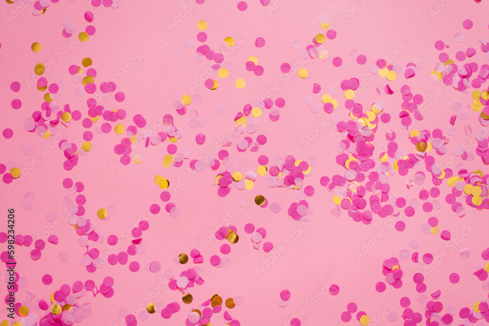 Gold and fuchsia confetti on a trendy pink pastel background. A festive background for your projects.