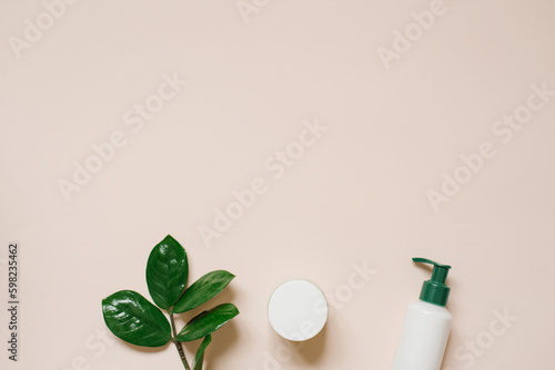 Set of organic SPA cosmetics with green leaves. Top view of bottles made of white recyclable plastic on a beige background Packaging design of natural cosmetics for skin care.
