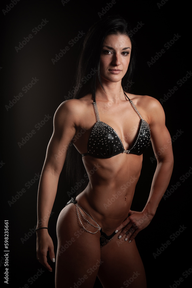 Fitness girl - attractive young woman working out with dumbbells in fitness gym - conceptual image for healthy lifestyle	