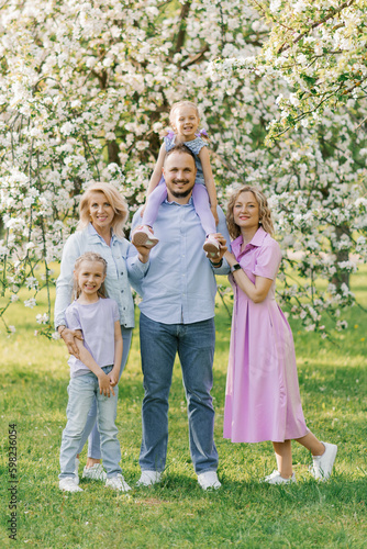 Portrait of a Caucasian family, parents, two daughters and a grandmother in a blooming spring garden © Sunshine