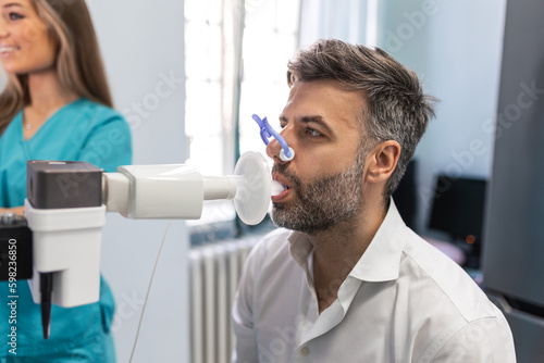Foto Man performing pulmonary function test and spirometry using spirometer at medical clinic