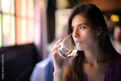 Serious woman drinking water in a restaurant