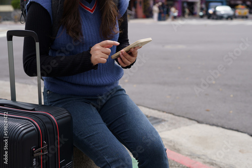 Woman with baggage in downtown city street searching location in map application online on smart phone using GPS navigating.