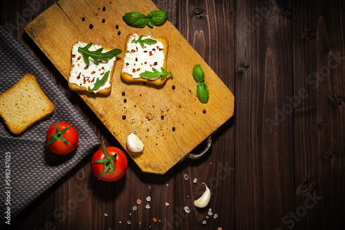 Breakfast photo of cream cheese and bread sliced. Tomato on wooden background.