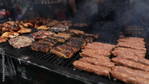 Romanian traditional mici (mititei), grilled ground meat rolls in cylindrical shape and other meats on the barbecue grill.