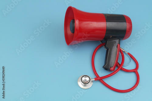 Red stethoscope and loudspeaker on blue background with copy space for text. Medical information concept.