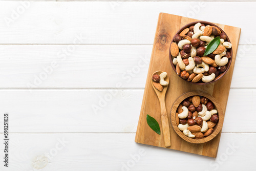 Assortment of nuts in wooden bowl on colored table. Cashew, hazelnuts, walnuts, almonds. Mix of nuts Top view with copy space