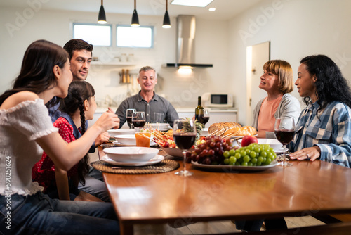 Multi-ethnic big family having dinner, enjoy evening party in house. 