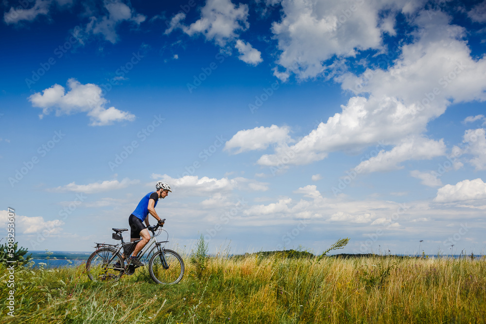 young athletic man on a bicycle riding the green meadow trail on sunny day young athletic man on a bicycle riding the green meadow trail on sunny day